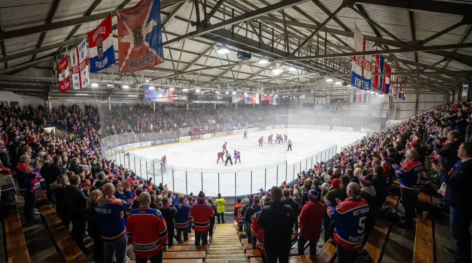 Crowd watching an EIHL ice hockey game in a packed British arena with team banners