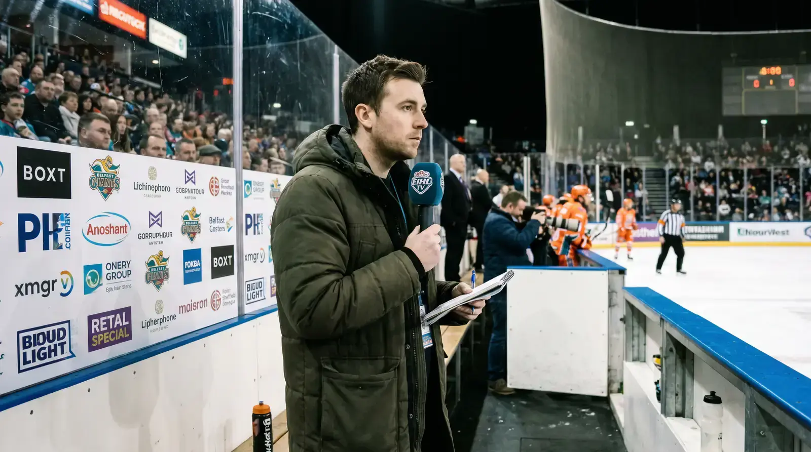 Hockey reporter with a microphone at rinkside during an EIHL game