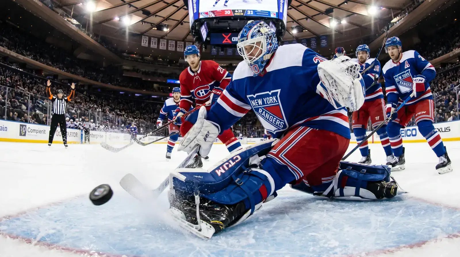 Goaltender in butterfly position blocking a shot during a busy NHL game