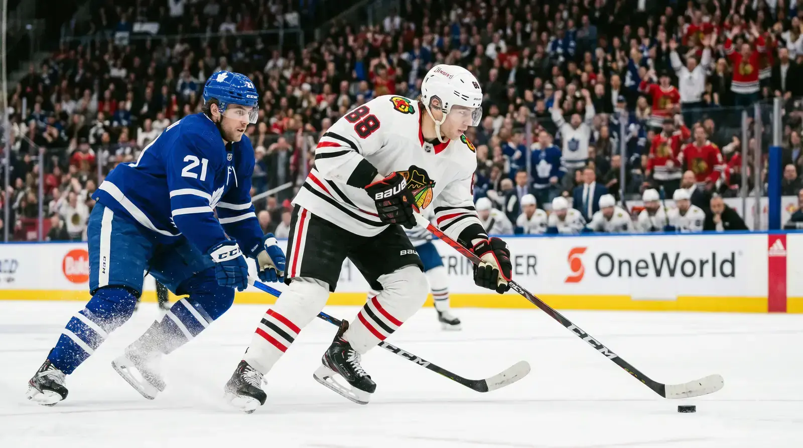 Hockey forward skating with the puck under pressure from a defending opponent